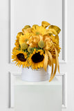 Yellow flower arrangement with sunflowers in a white box on a white background